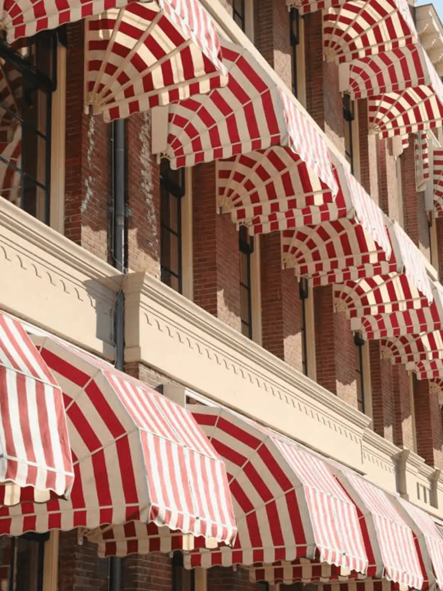 Rows of red and white striped awnings on the brick facade of Fosbury & Sons